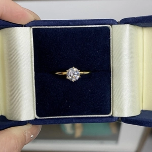 Macro detail of a 1-carat moissanite ring with six-prong gold setting in a velvet box