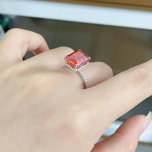 Détail macro d'une bague avec pierre rouge orangé taille radiant et serti micro-pavé argent