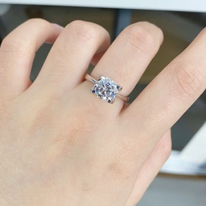 Classic 2-carat Moissanite ring on finger with four-claw silver setting in bright natural light