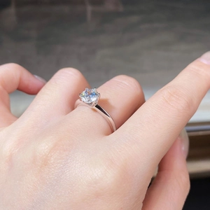 Detailed close-up of a classic six-prong moissanite ring on a finger with brilliant sparkle