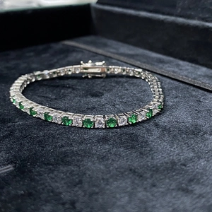 Macro view of S925 silver tennis bracelet with green emerald stones and white diamonds