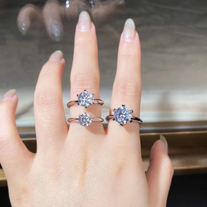 Macro shot of three different carat sizes of six-prong moissanite rings on a hand