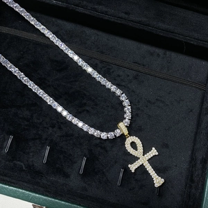 Gros plan sur une chaîne tennis hip hop avec pendentif croix Ankh dorée pavée de pierres