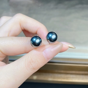 Detailed close-up of dark blue Tahitian pearl earrings with metallic luster held in hand