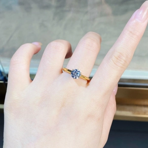 Detail of a 18k gold plated S925 silver six-prong moissanite ring worn on a finger