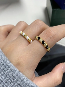 Close-up of gold ring set with spiral black and white enamel and zircon stones
