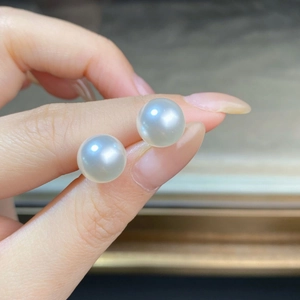 Detail shot of 8-10mm round white S925 silver pearl earrings held by hand