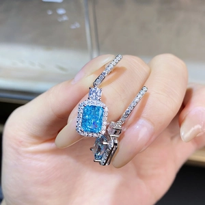 Elegant S925 silver aquamarine earrings with rectangular halo diamond setting held by hand