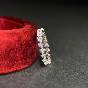 Macro shot of S925 sterling silver eternity band with heart-cut stones on red velvet