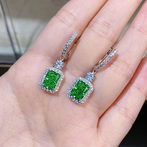 Macro shot of S925 sterling silver emerald-cut green crystal earrings with halo diamonds
