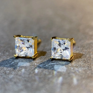 Macro view of classic princess cut moissanite earrings in gold four-prong setting
