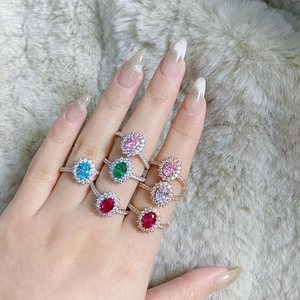 Close-up of model wearing seven colorful halo-set oval gemstone rings on plush fabric