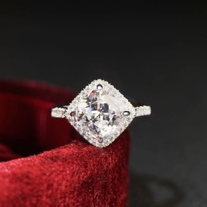 Détail macro d'une bague en argent taille coussin avec halo dans un écrin rouge