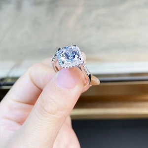 Gros plan d'une bague en argent avec coupe coussin, monture halo et pavé de diamants