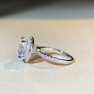Side view of oval cut moissanite ring with halo setting and micro-pave silver band