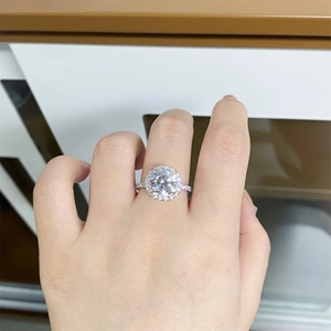 Detail of round cut moissanite halo ring with pavé band worn on a finger