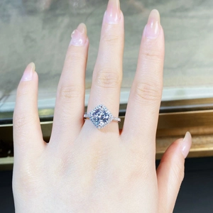 Gros plan d'une bague de fiançailles taille coussin avec halo et pavé de diamants