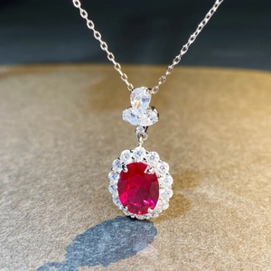 Vue macro d'un pendentif ovale avec pierre rouge et entourage de diamants scintillants