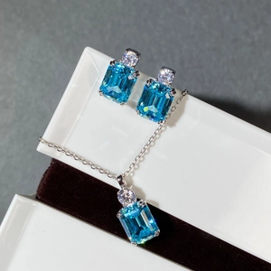 Macro view of emerald cut aquamarine zircon earrings and pendant in a silver setting