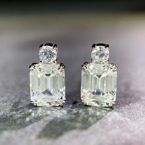 Macro shot of 925 silver stud earrings featuring emerald-cut and round-cut clear gemstones