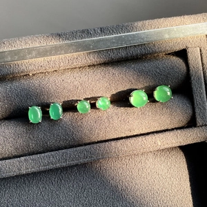 Detailed view of three emerald green chalcedony silver stud earrings in a jewelry box