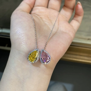 Dettaglio di pendenti a goccia gialli e rosa con alone di zirconi su catena d'argento