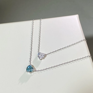 Détail de pendentifs en moissanite vert menthe et blanc en forme de cœur sur chaînes