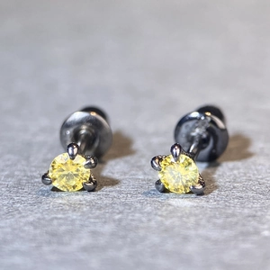 Macro shot of yellow round diamond stud earrings set in dark black claw settings