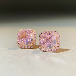 Vue macro de boucles d'oreilles rose taille radiant avec entourage pavé en or rose poli