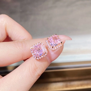 Gros plan détaillé de boucles d'oreilles en or rose avec pierre rose carrée et diamants