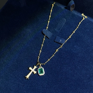 Macro shot of 18K gold-plated S925 silver necklace with emerald pendant and diamond cross