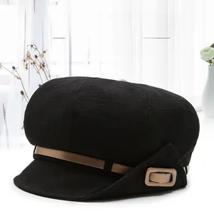 Detail of black cotton-linen beret featuring brown leather strap and metal buckle