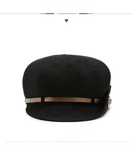 Front view of black newsboy cap with brown leather decorative strap and metal buckle