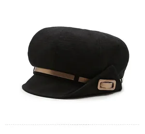Detail of black newsboy cap featuring textured fabric and a decorative gold metal buckle