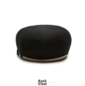 Back view detail of black woven baker boy hat featuring textured fabric and tan leather trim