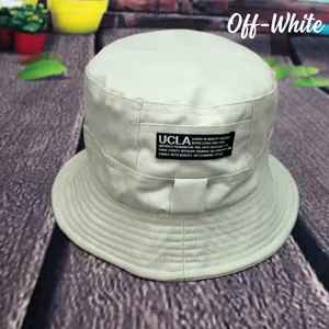 Detailed close-up of UCLA logo patch on cream cotton reversible bucket sun hat