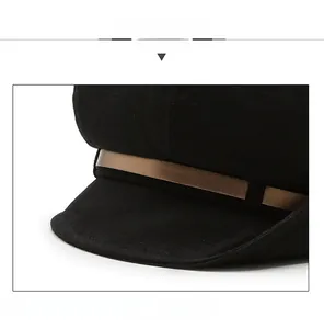 Detail view of black baker boy hat featuring textured fabric and decorative bronze trim