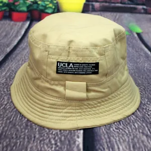Detail of beige cotton bucket hat featuring a black textile label and stitched brim detail