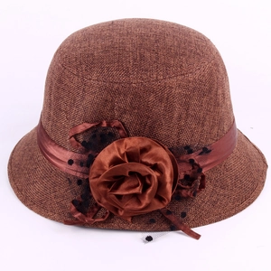 Detail of brown linen cloche hat with satin ribbon, handmade flower and polka dot mesh
