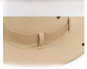 Detail of ripstop fabric texture and metal ventilation eyelet on a beige outdoor hat