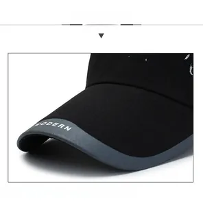 Dettaglio del cappellino nero con bordo grigio e ricamo bianco sulla parte laterale