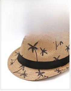 Détail du chapeau fedora en paille d'été avec imprimés palmiers noirs et ruban tissé