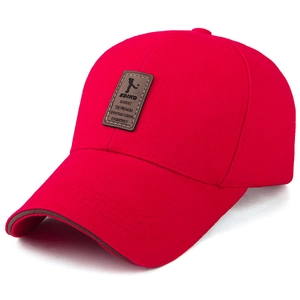 Detail view of red cotton baseball cap with brown leather brand patch and long brim