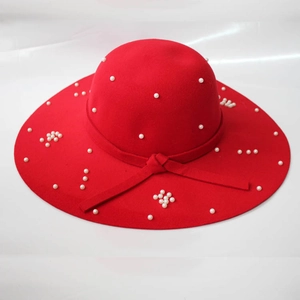 Détail d'un chapeau en laine rouge avec perles blanches élégantes et nœud en ruban assorti