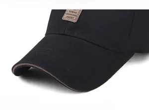 Detail of black cotton baseball cap with leather patch and brown piped brim edges