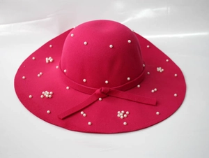 Détail d'un chapeau en feutre fuchsia à large bord avec perles blanches et nœud