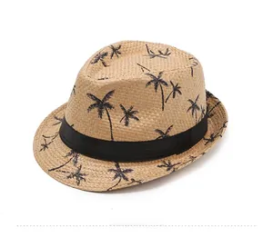 Détail d'un chapeau de paille d'été avec imprimés palmiers noirs et ruban noir élégant
