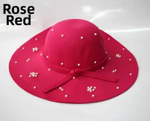 Détail d'un chapeau en laine rose rouge à large bord avec perles et nœud élégant