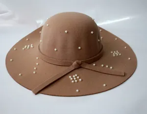 Détail d'un chapeau en laine camel orné de perles blanches élégantes et de motifs