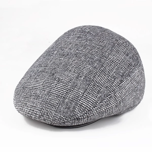 Dettaglio cappello invernale grigio a quadri con tessuto spazzolato e bordo in pelle